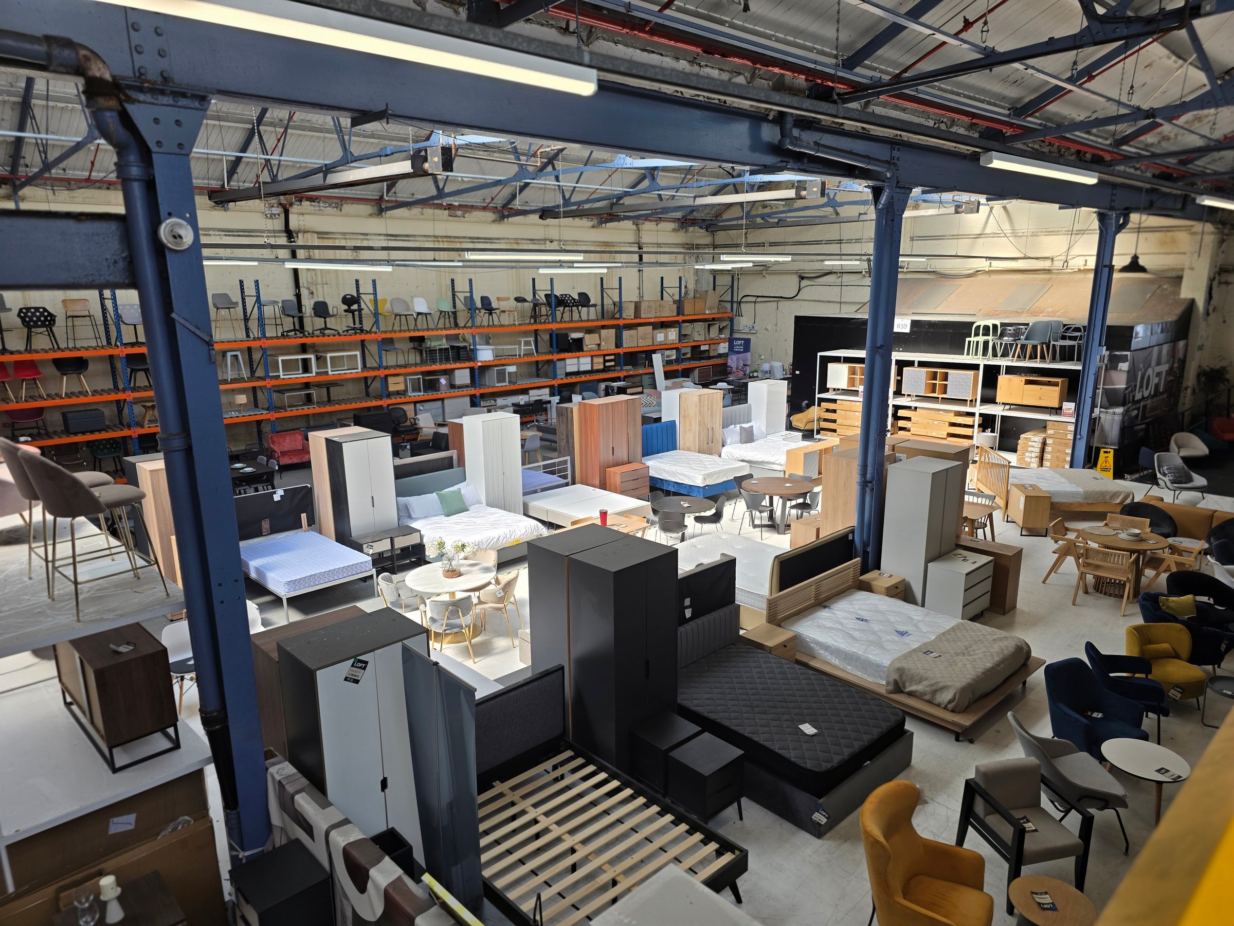 LOFT warehouse outlet with various furniture items including beds, tables, and chairs.