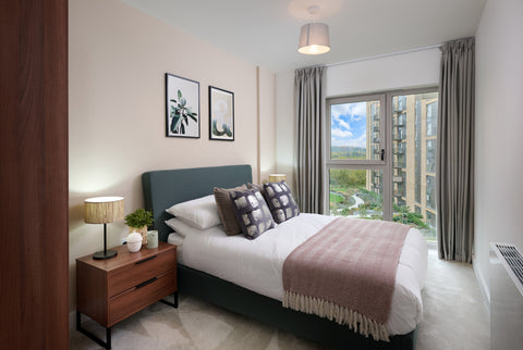 Modern bright apartment bedroom, with bed, side table and wardrobe, with a window overlooking greenery
