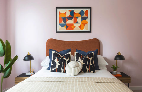 Bedroom with a bed, pillows, nightstands, and a colorful abstract painting on the wall.