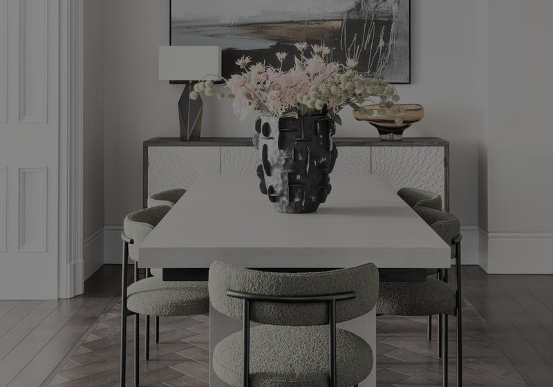 Dining room with a table and chairs, featuring a vase with flowers on the table.