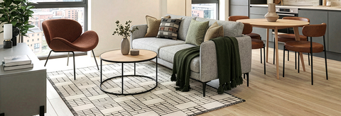 Modern living room with a gray sofa, wooden coffee table, and chairs.