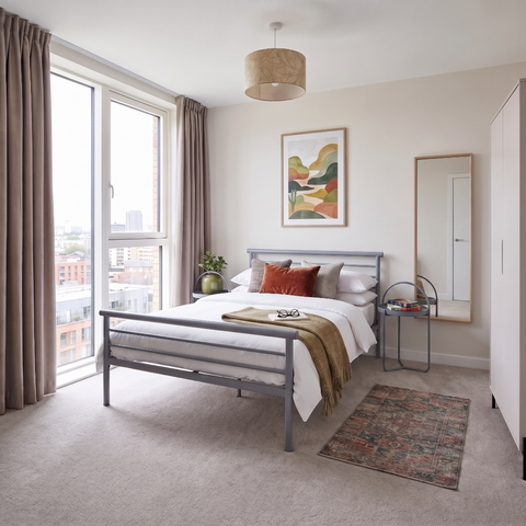 bedroom with metal bedframe, side tables, mirror and wardrobe
