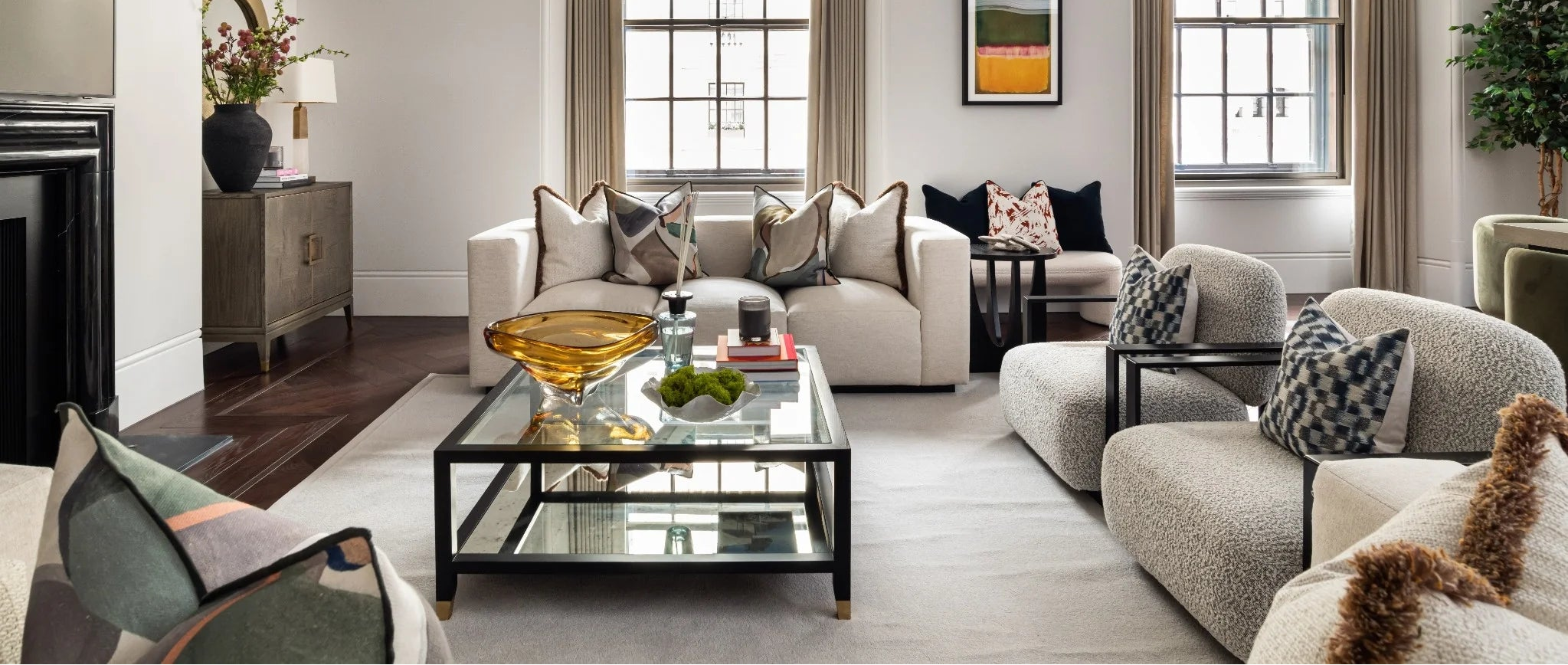 Modern living room with gray sofa, glass coffee table, and decorative pillows.