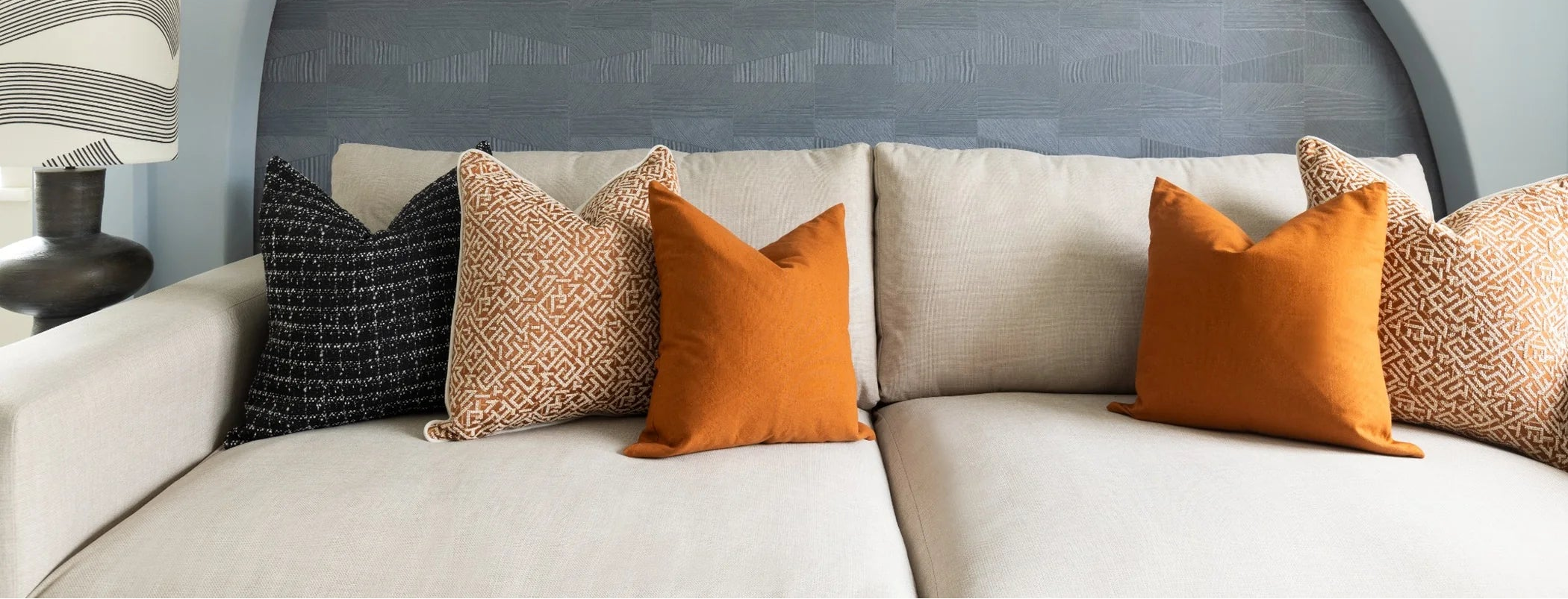 Beige sofa with colorful pillows against a gray wall